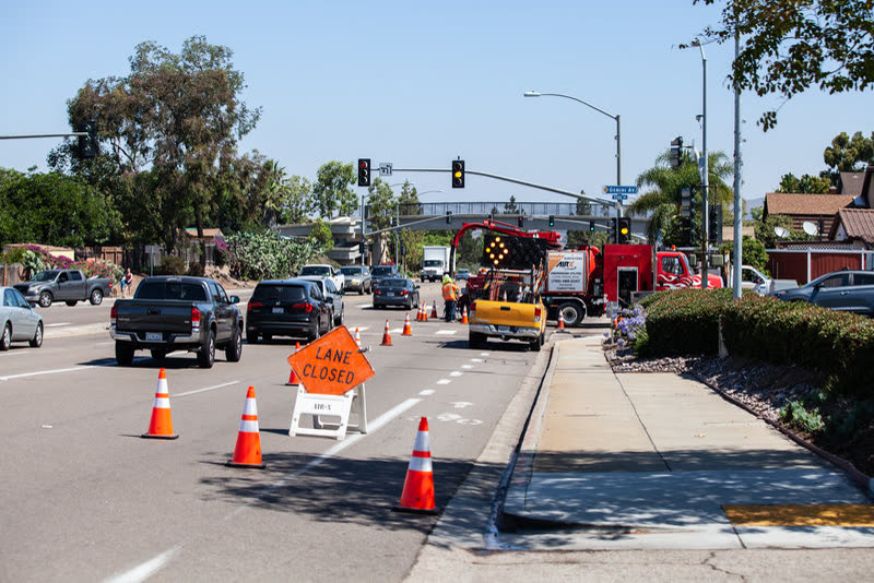 A closed lane marked out with cones and a LANE CLOSED sign, an arrow board truck at the far end.